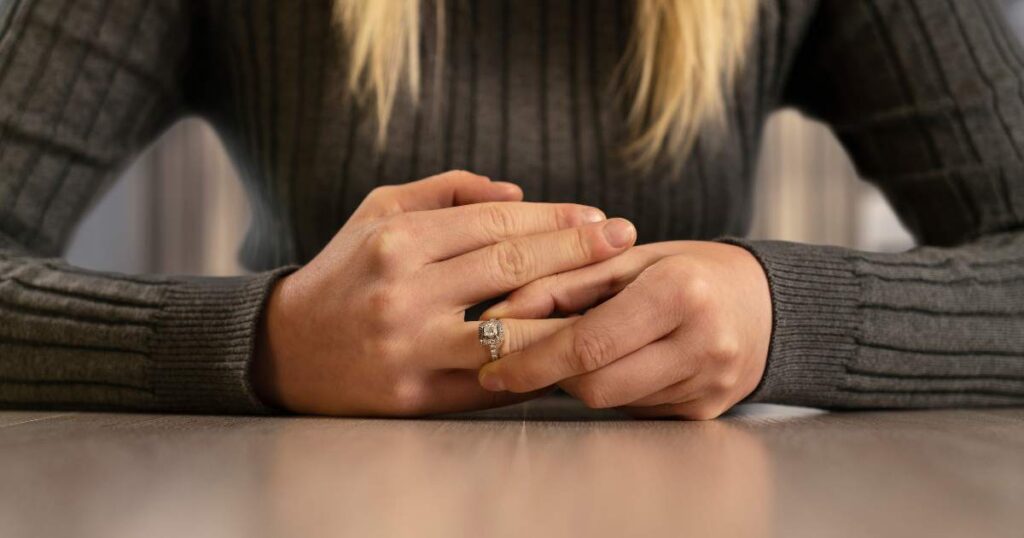 woman removing a ring on her finger implying an end to a relationship with either a separation or divorce