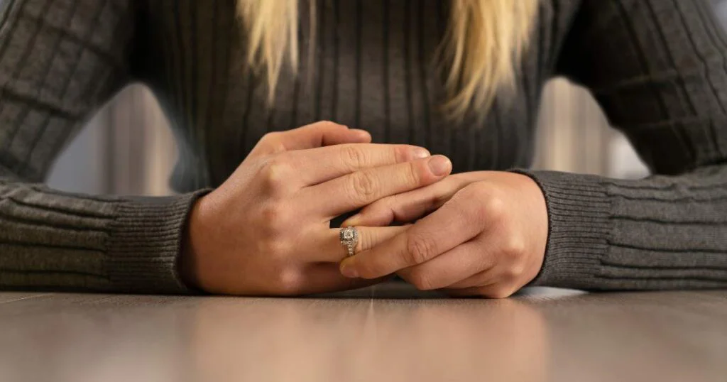 woman removing a ring on her finger implying an end to a relationship with either a separation or divorce