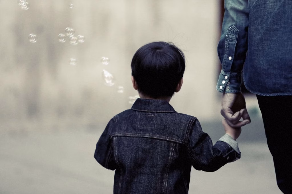 A little boy is holding hands with a parent while walking.