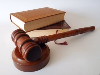 A gavel and legal texts on a white background illustrate the judicial process involved in establishing parenting orders.