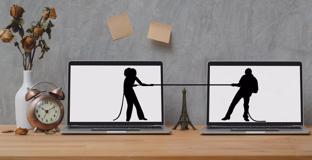 Two laptops show silhouettes of individuals engaged in a tug-of-war, illustrating the challenges of protecting assets in divorce.